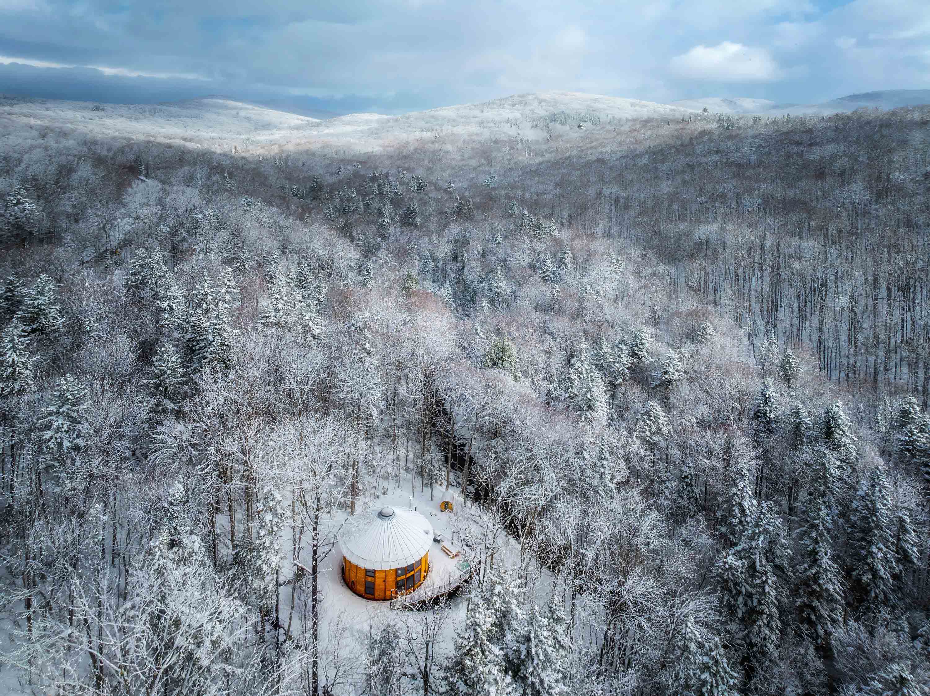 <span class="uc_style_uc_tiles_grid_image_elementor_uc_items_attribute_title" style="color:#ffffff;">55. Sweeping Aerial View of Luxury Yurt in Secluded Snow-Covered Forest Setting with Distant Mountains, Hot Tub, Sauna, Starlink, EV Charger - Mount Snow Yurt</span>